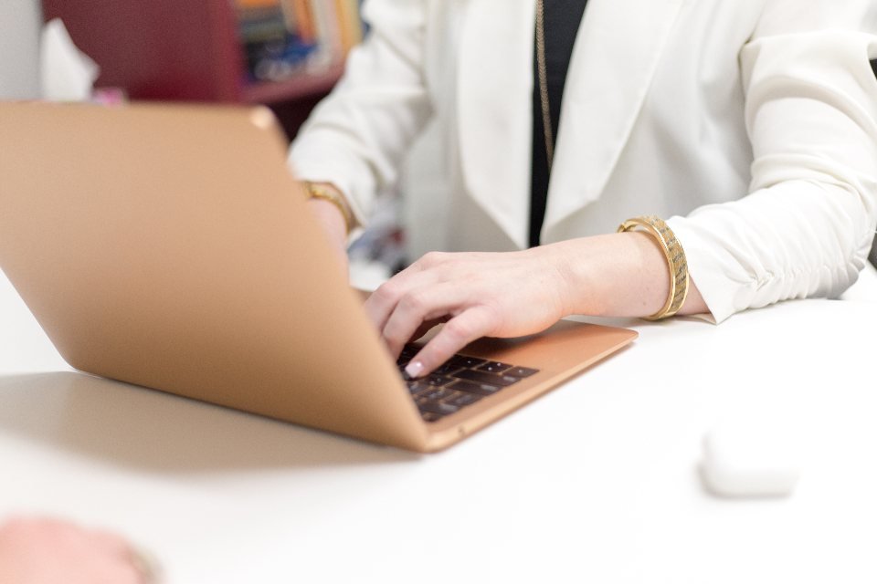 Tay người phụ nữ gõ phím laptop trên bàn trắng — cách viết content bán hàng hiệu quả