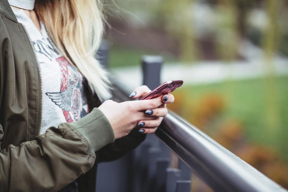 Người phụ nữ đứng ngoài trời nhắn tin trên điện thoại — khách đọc content bán hàng trên điện thoại