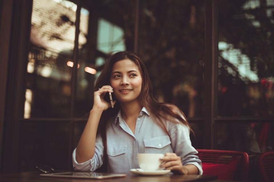 Người phụ nữ nghe điện thoại trong quán — khách nhắn tin từ fanpage