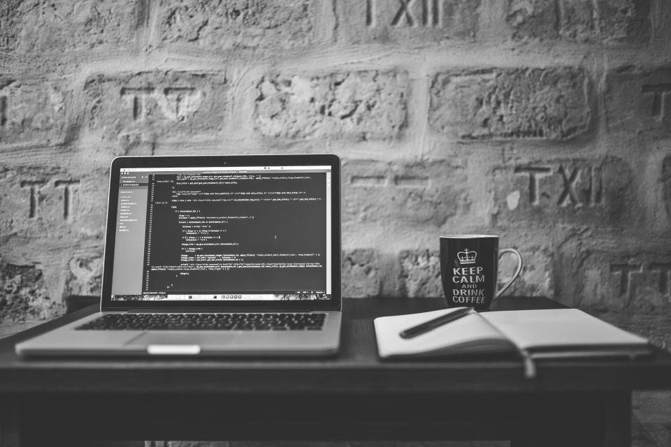 Laptop, sổ tay và cốc cà phê trên bàn gỗ — soạn dàn ý kinh doanh khoá học online